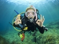 Young woman scuba diving signals okay